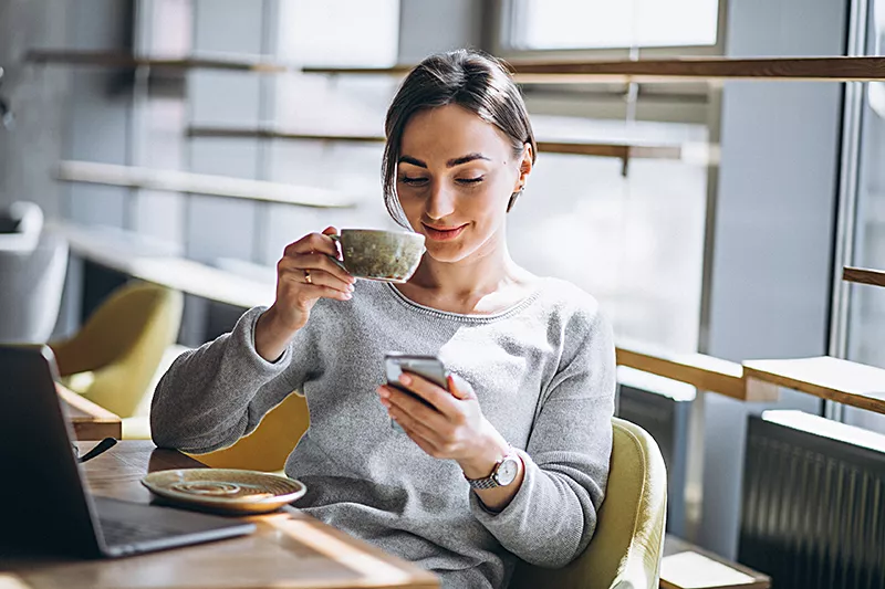 woman-sitting-in-cafe-drinking-coffee-and-working-on-computer